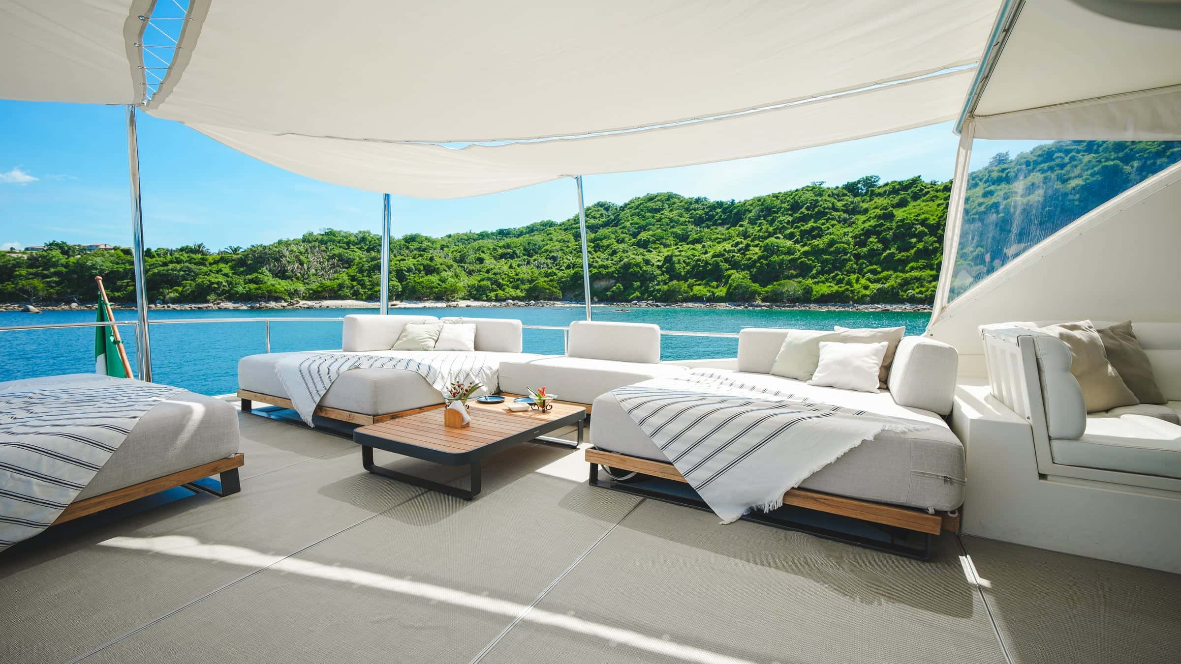 Flybridge lounge with daybeds, sofas and a coffee table under a canopy