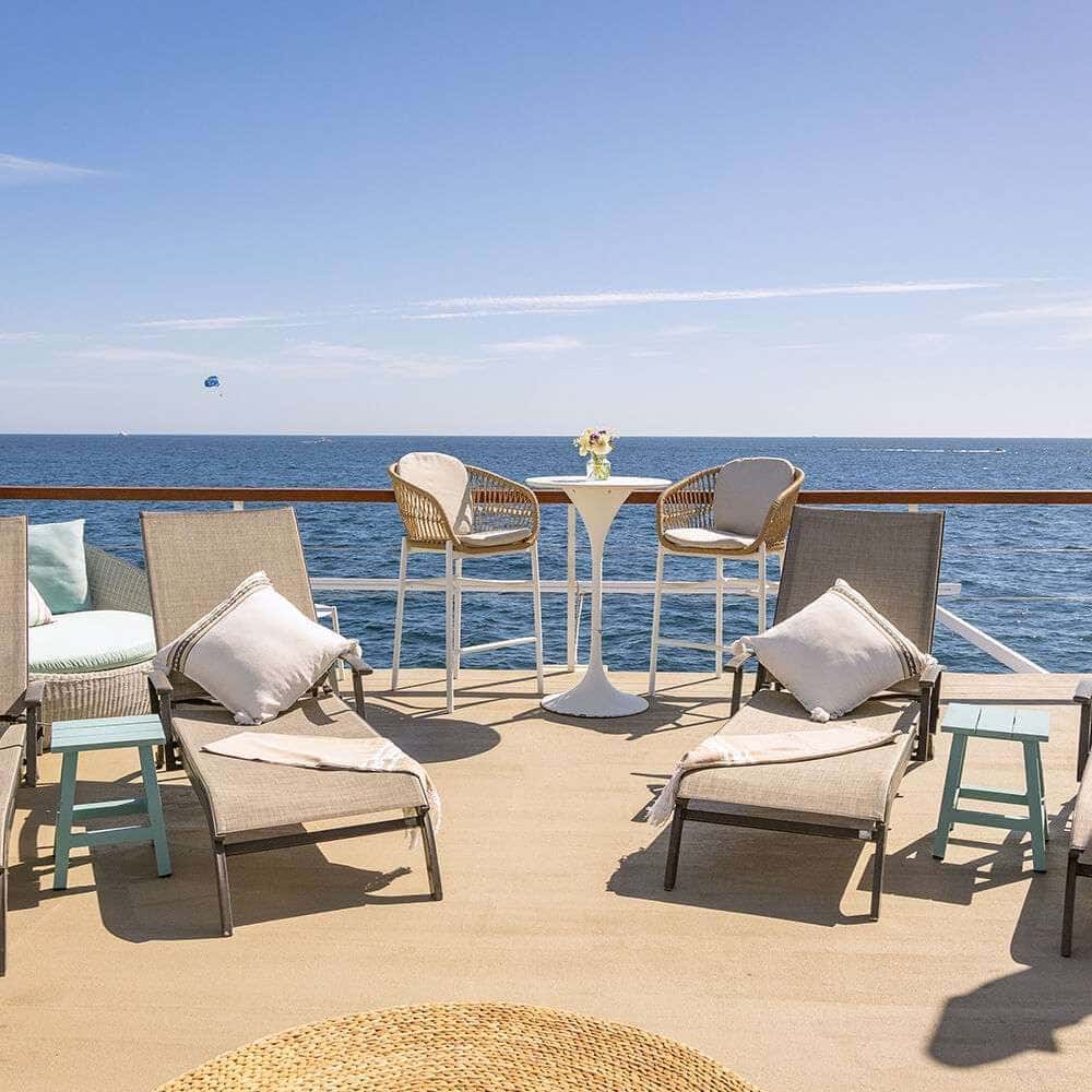 Cushioned sun loungers and a high table at the rail of the open upper deck