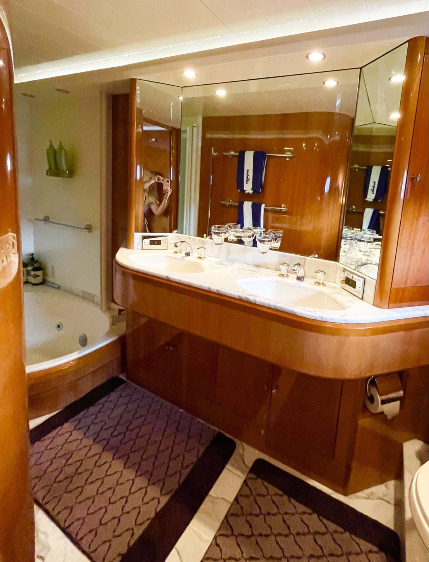 En-suite bathroom in wood and marble with twin basins, a wide mirror and a jetted tub