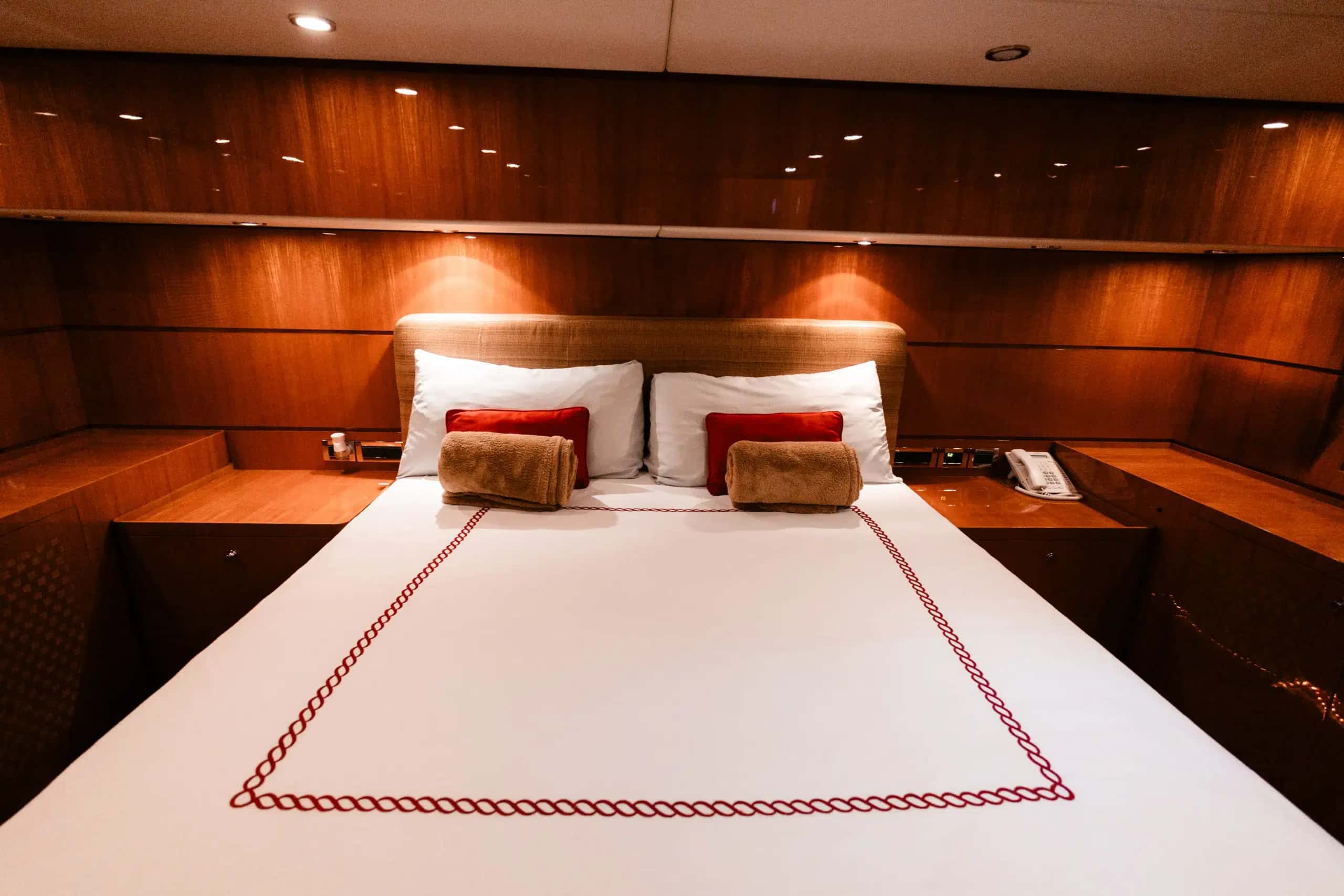 A double cabin, the white bed trimmed in red under wood panelling.