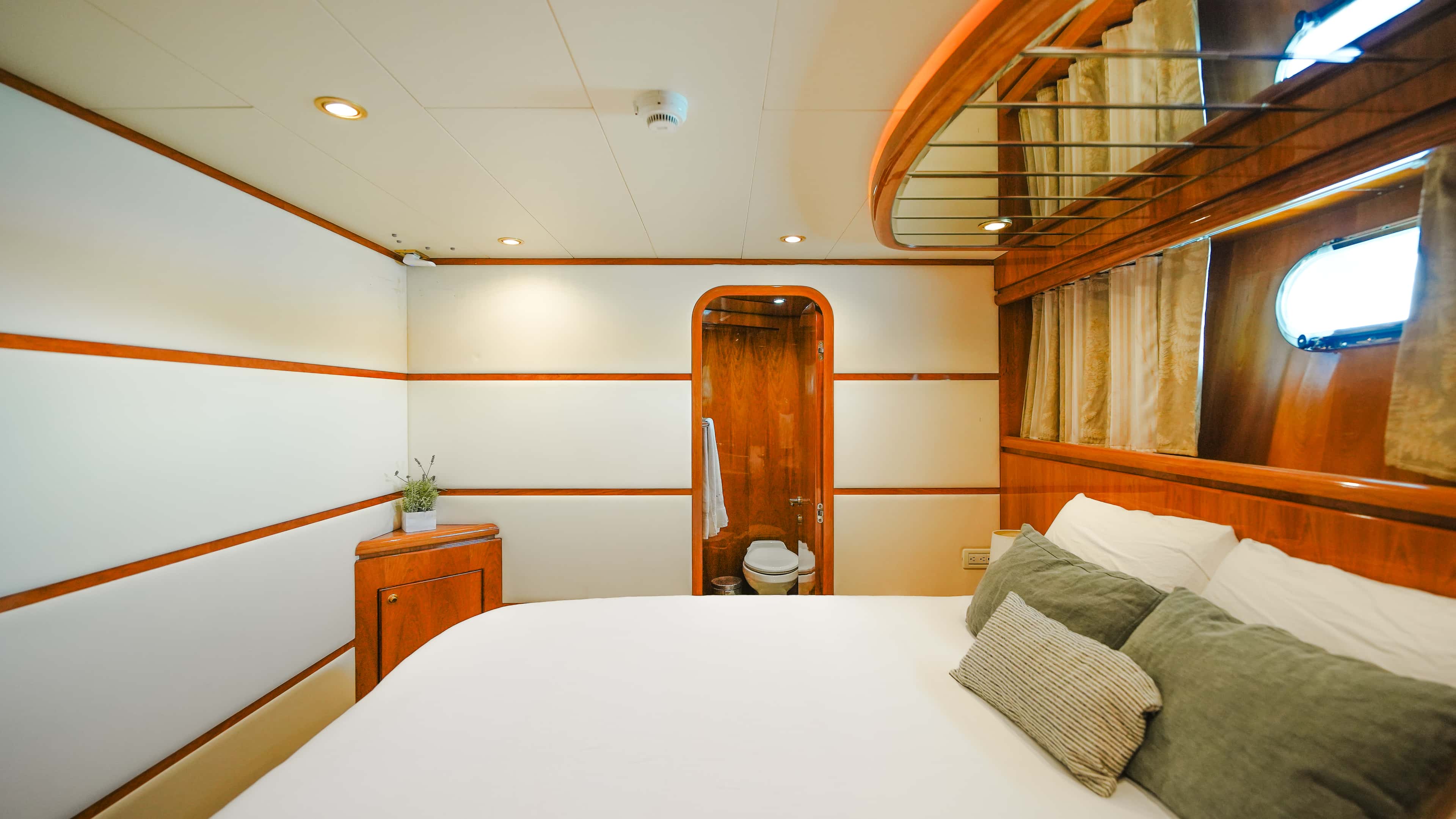 Guest One queen cabin with green cushions and a porthole, seen from the bed
