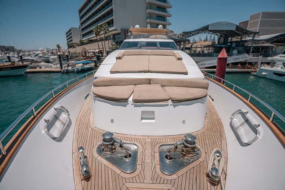 Looking aft along the teak foredeck to the sun pads in front of the windscreen, hotels across the marina