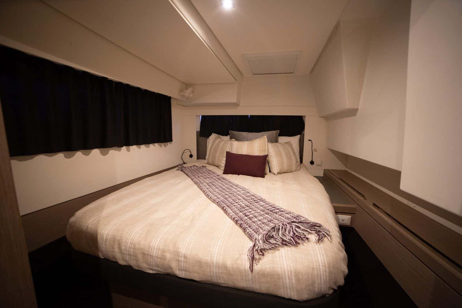 Double cabin with a long hull window, cream bedding and a striped throw