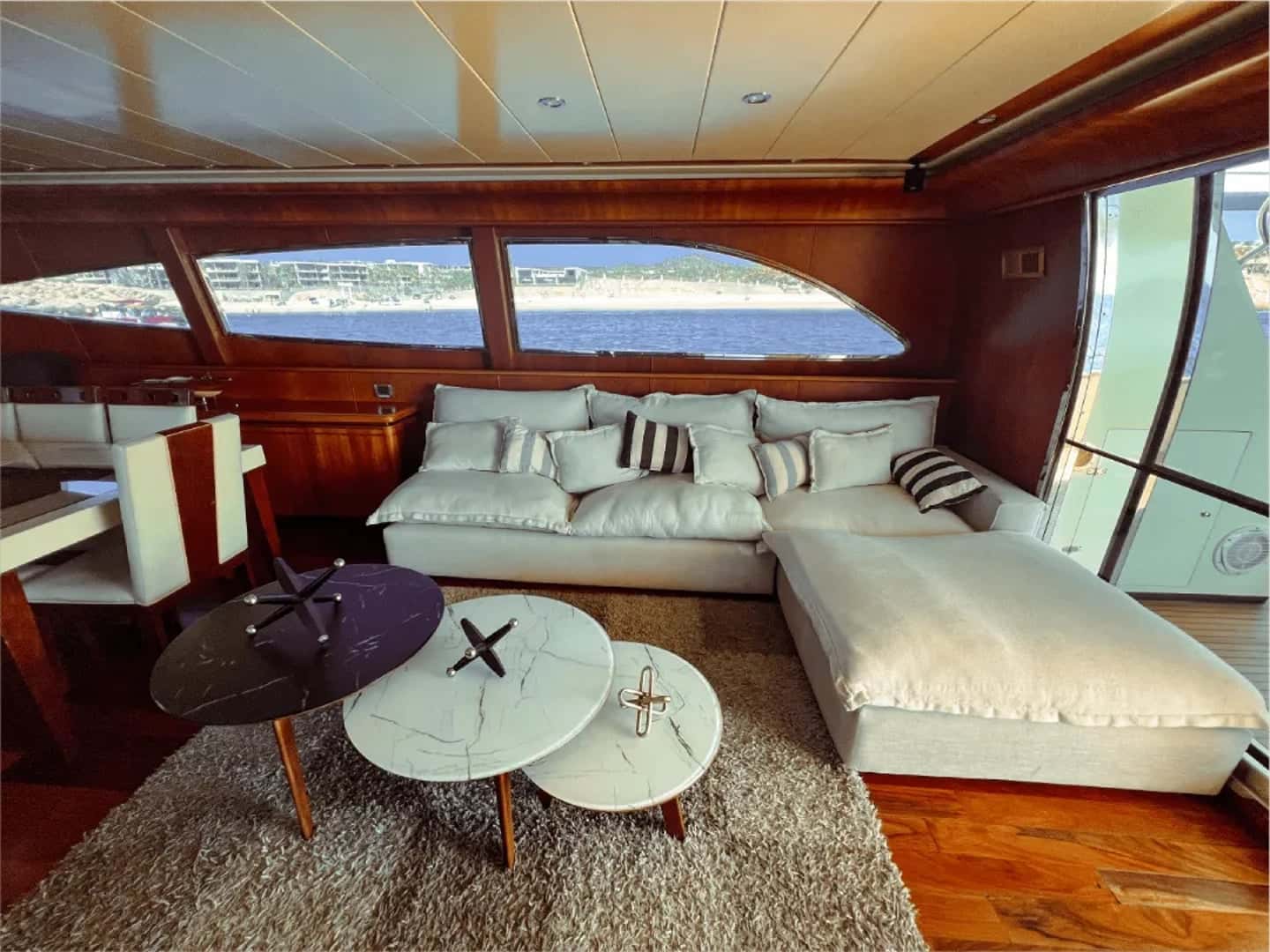 Saloon with a cream sectional sofa, round marble coffee tables and wide windows