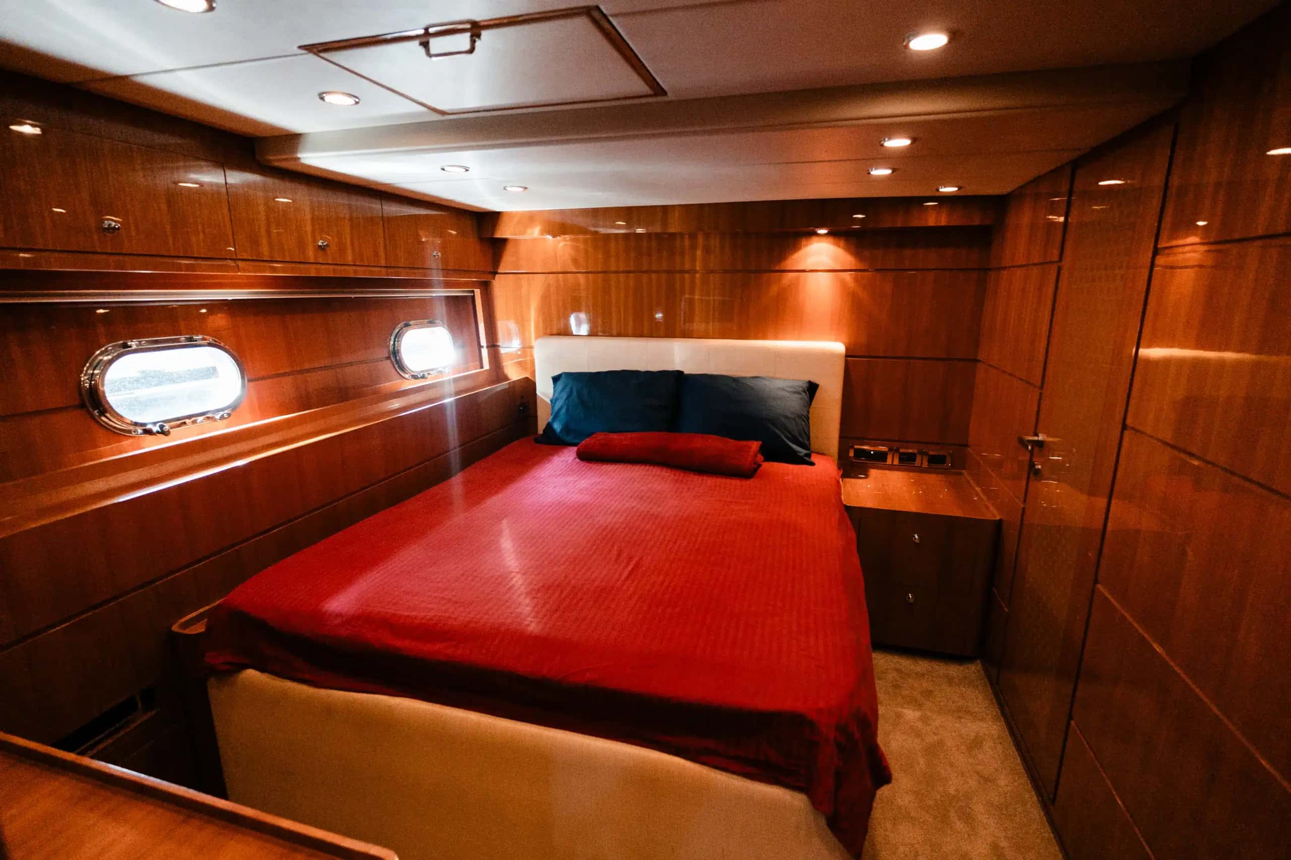 The second double cabin, a red cover on the bed and portholes either side.