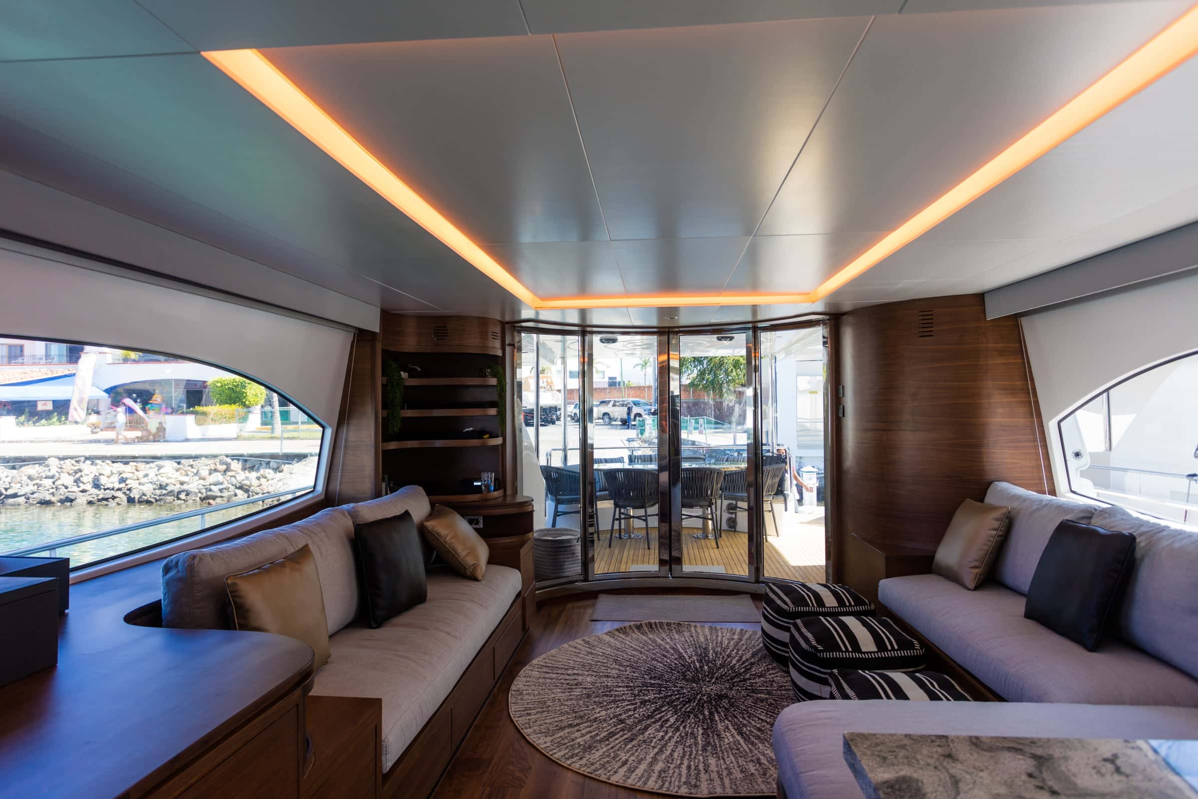 Saloon with long sofas, a round rug and a wood floor, glass doors open to the aft deck