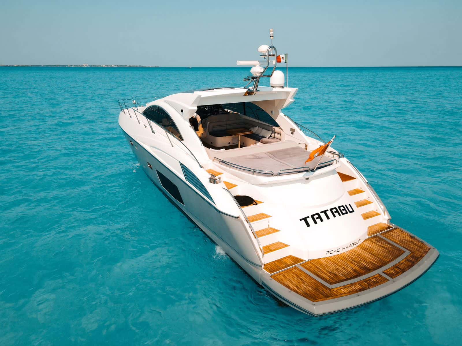 Tatabu from astern and above at anchor, with her name on the transom, the teak swim platform and the aft sun pad