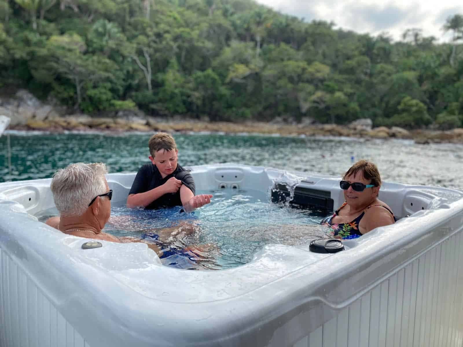 Three guests in the hot tub at anchor in a green cove