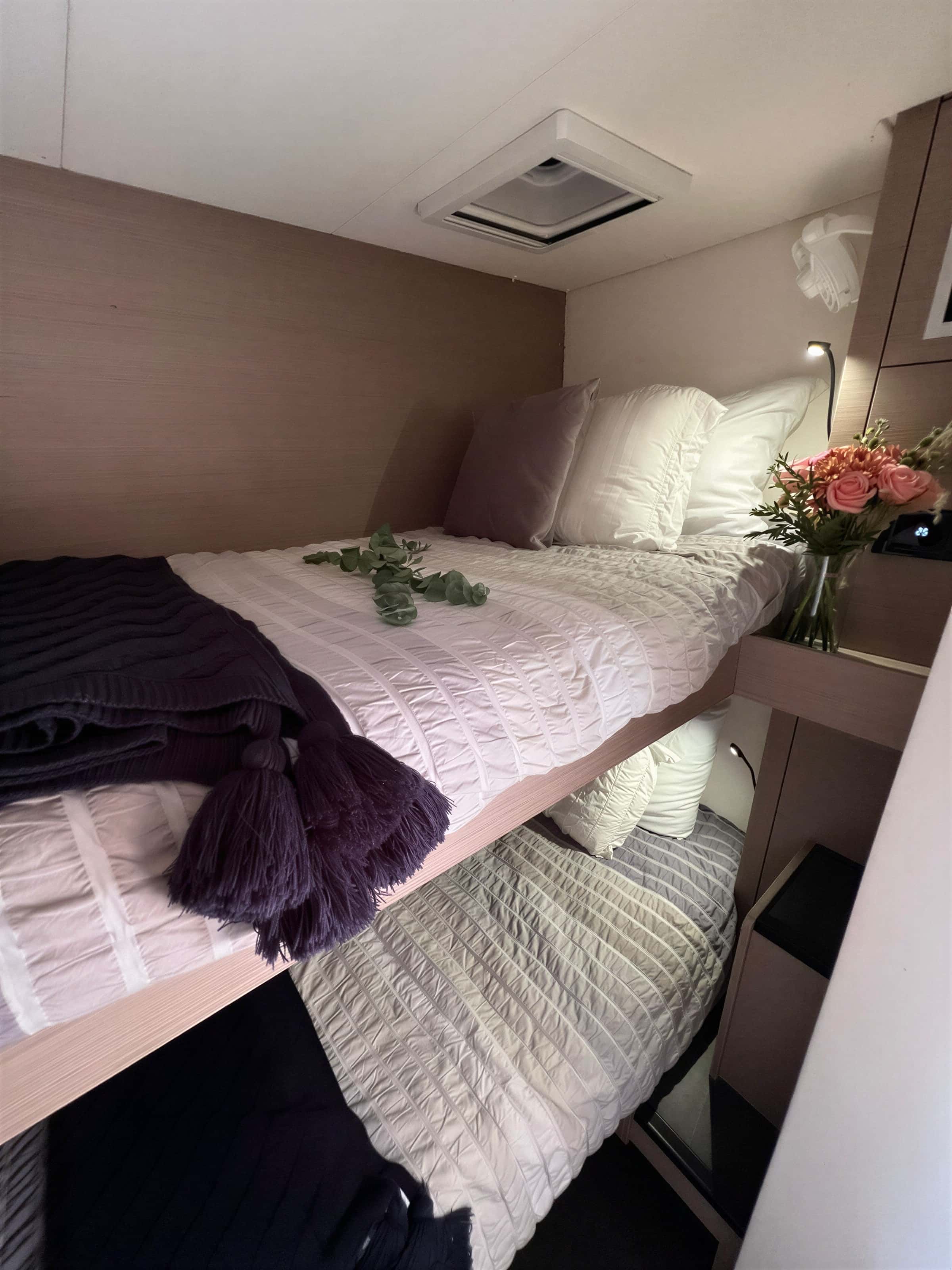 Bunk beds in a cabin, with white bedding, a purple throw and flowers