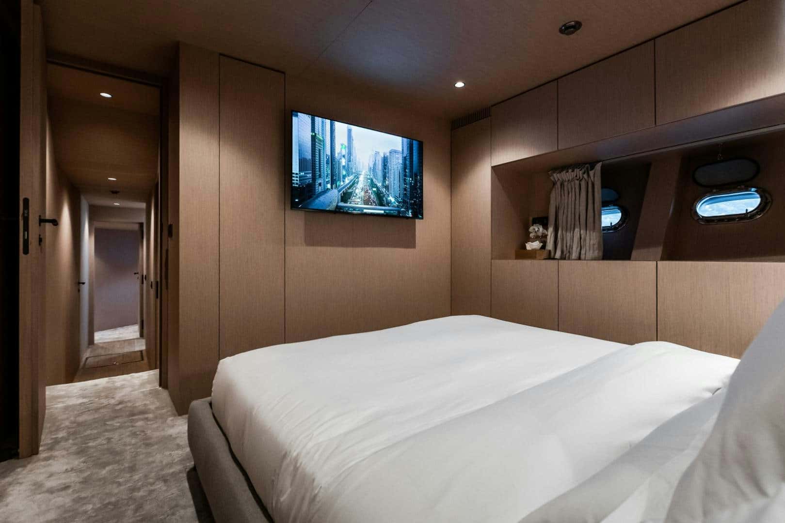 Double cabin with a wall-mounted TV and portholes above the bed