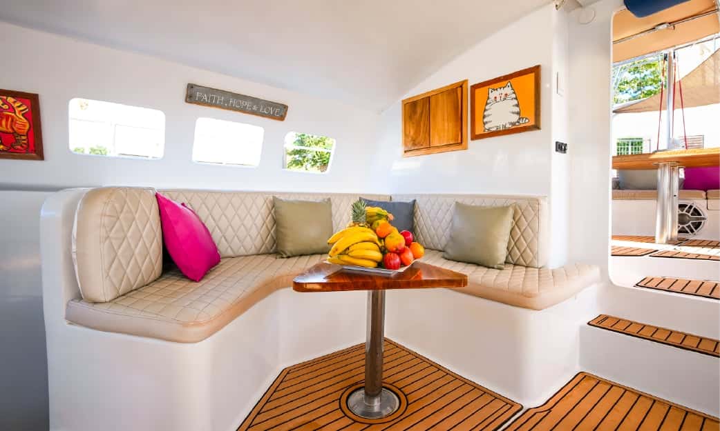 Cushioned corner sofa around a small table with a bowl of fruit in the saloon