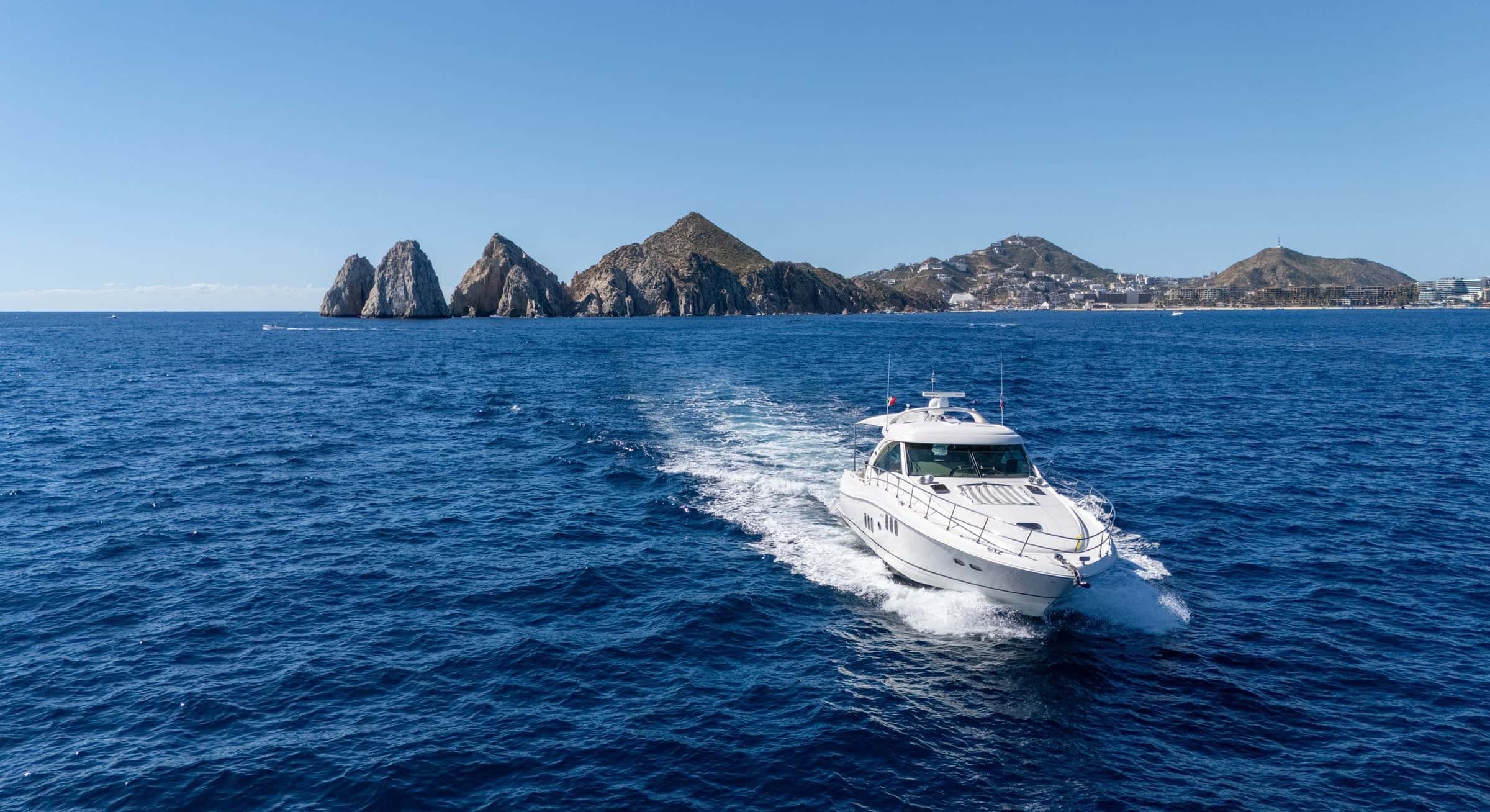 Steel Aweigh cruising toward the Arch of Cabo San Lucas, a white wake on deep blue water