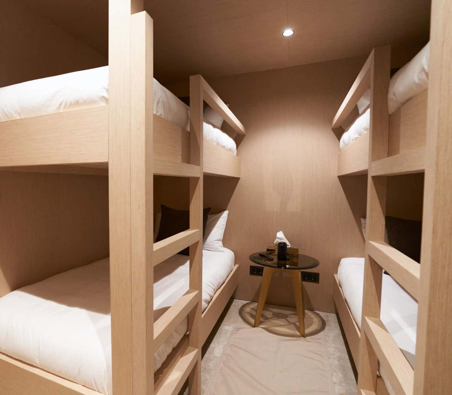 Bunk cabin with two sets of built-in oak bunks, white bedding and a small round table