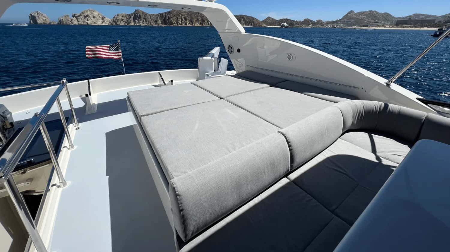 Flybridge with a large grey sunpad and curved seating, rocky coast in the distance