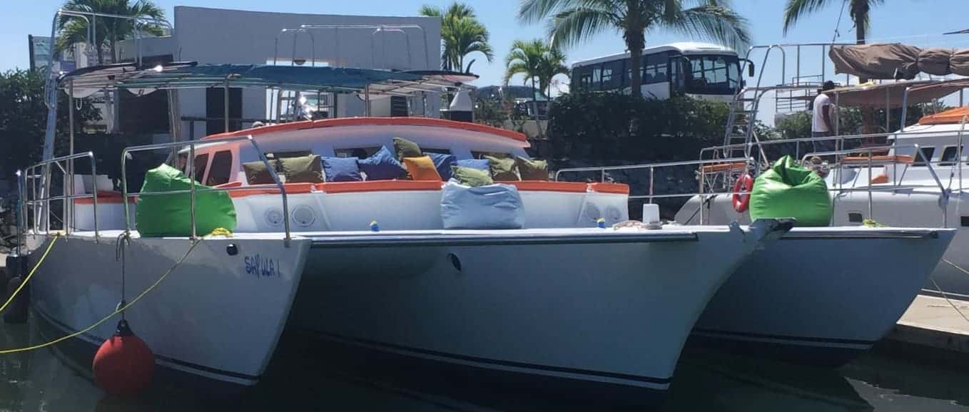 Trimaran moored at a marina dock, bow lounge with cushions and green bean bags