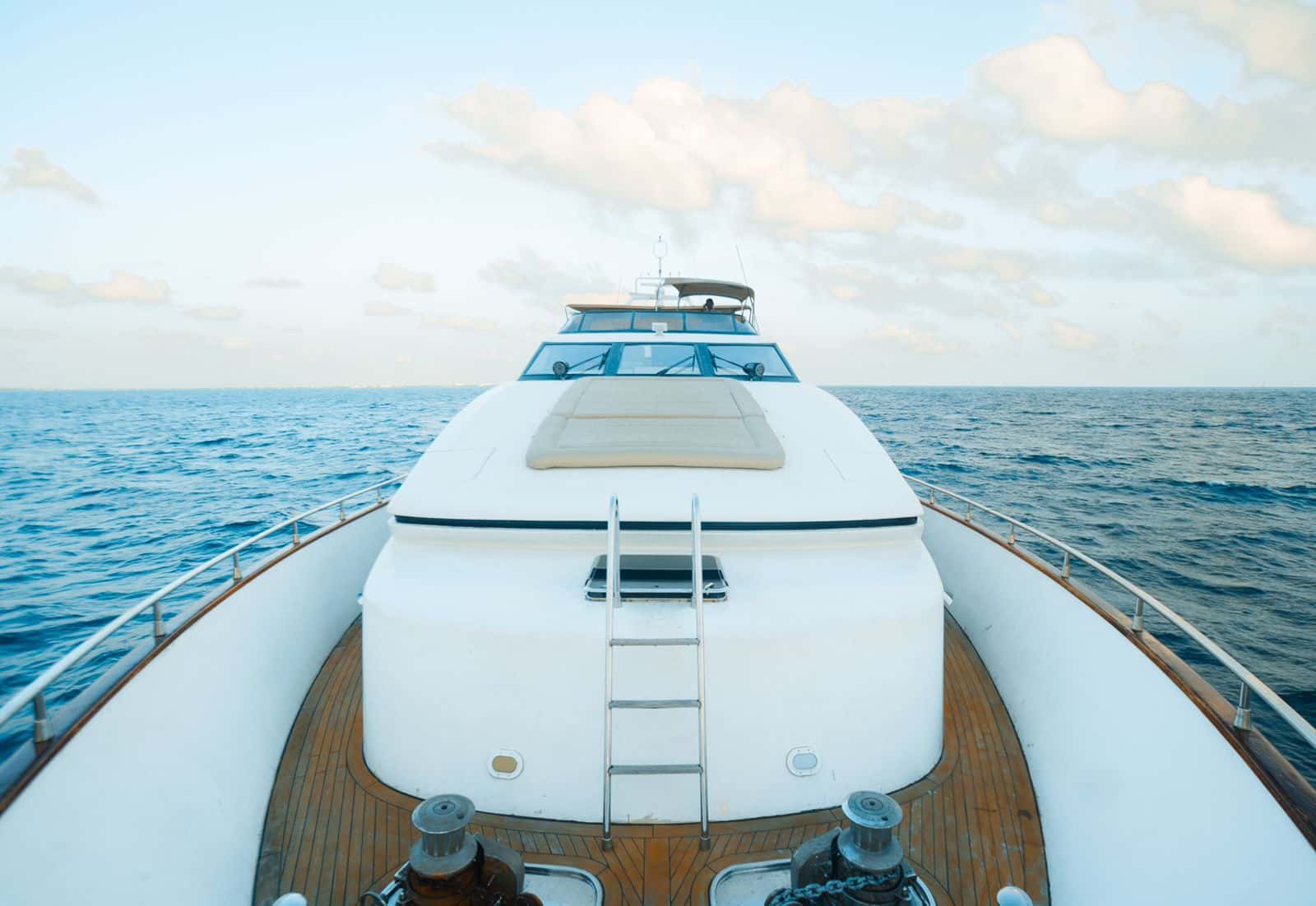 Teak foredeck and bow with a cushioned sunpad and ladder up to the bridge, open sea ahead