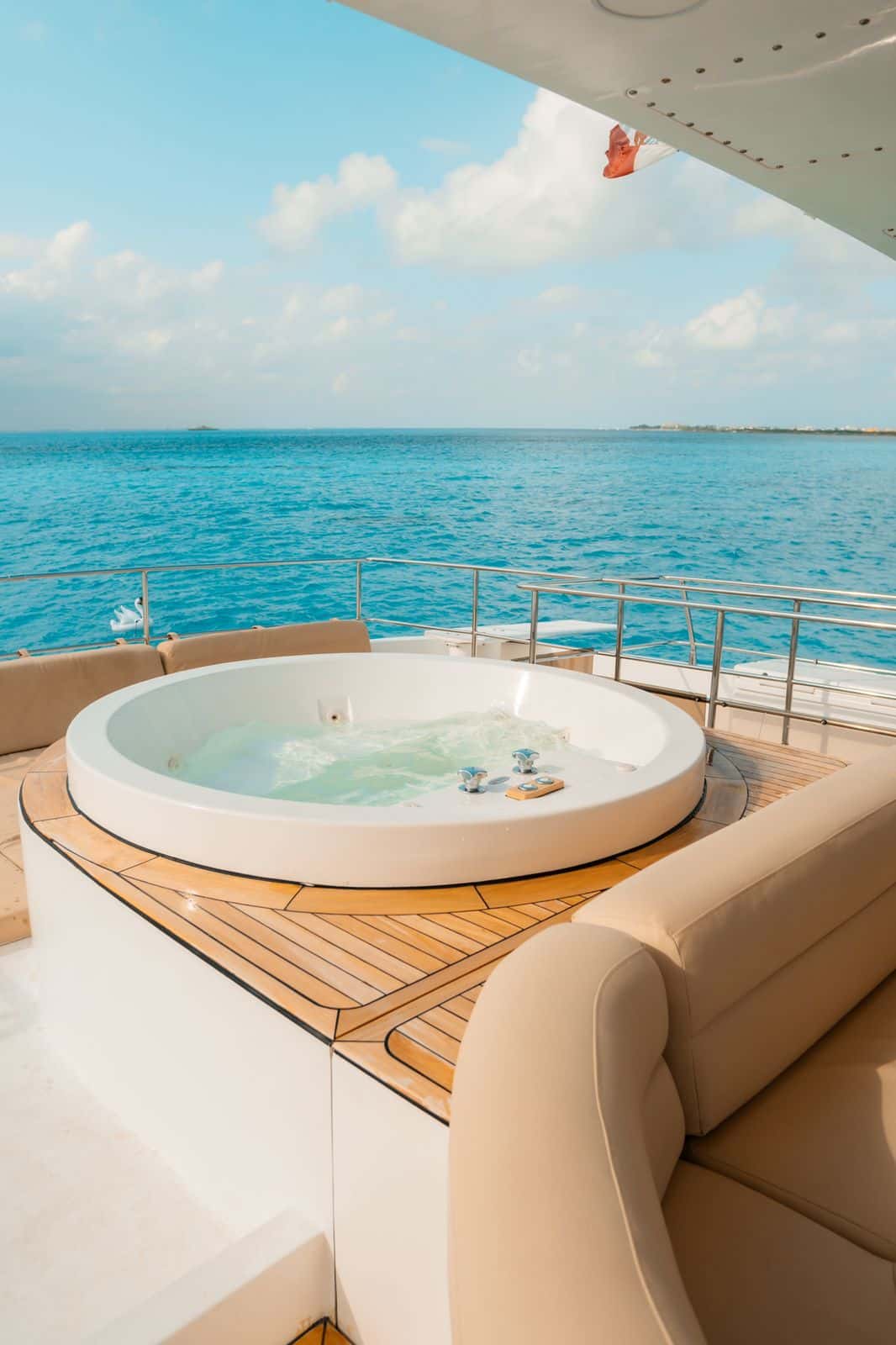 Round Jacuzzi set in a teak deck surround with cushioned seating and ocean view