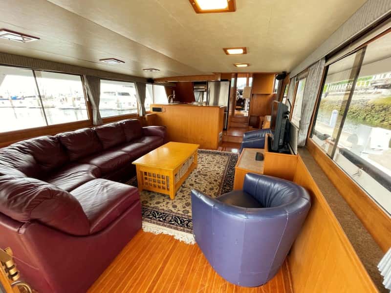 Salon with burgundy leather sectional, blue chairs, coffee table, TV and galley beyond