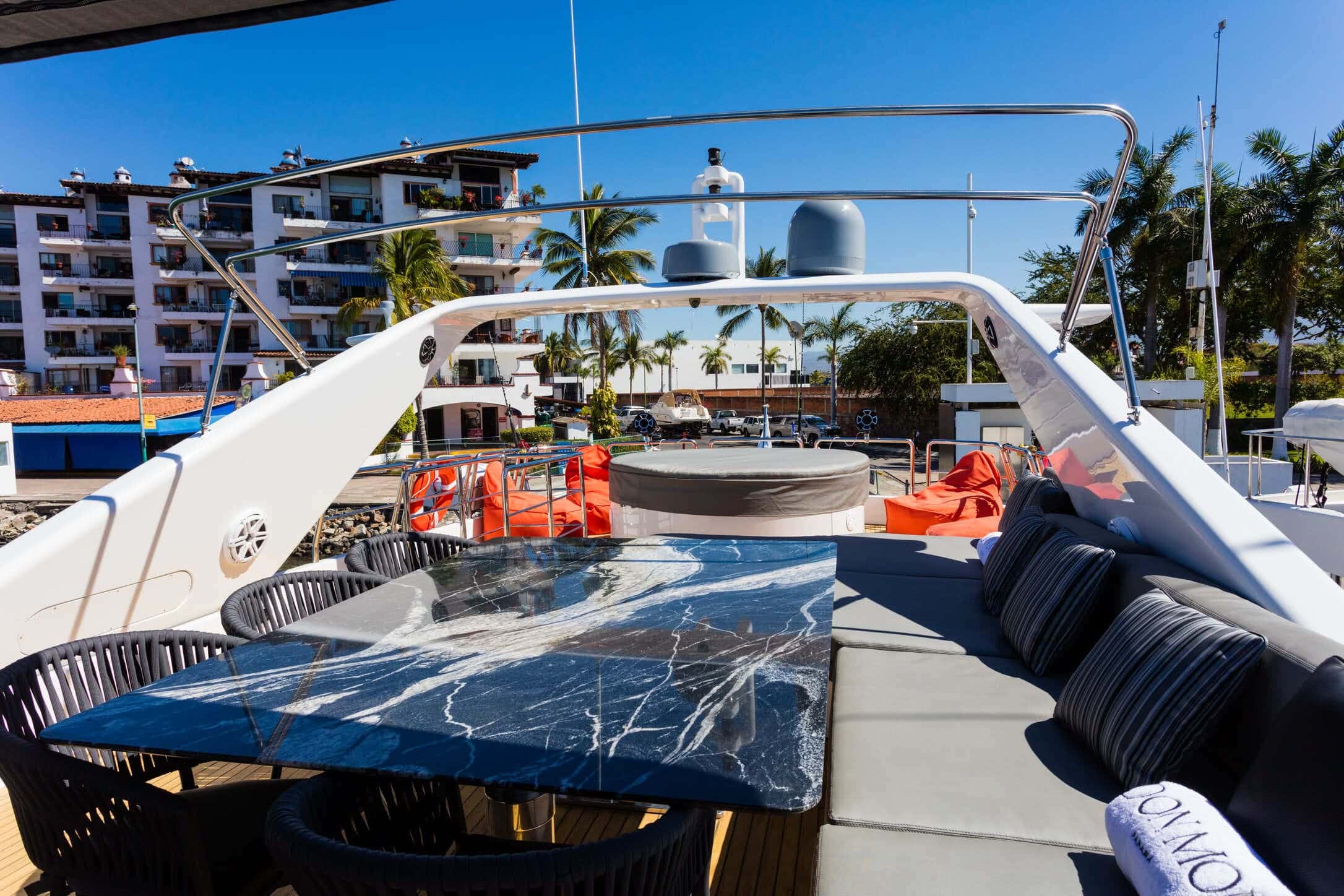 Flybridge with a black marble dining table, chairs, grey sofa and a jacuzzi under a cover
