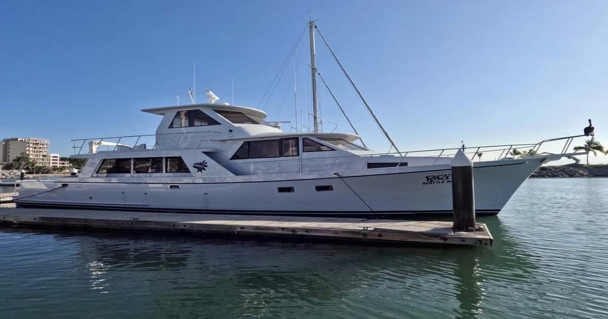 Brina, a white motor yacht, moored alongside a marina dock under a blue sky