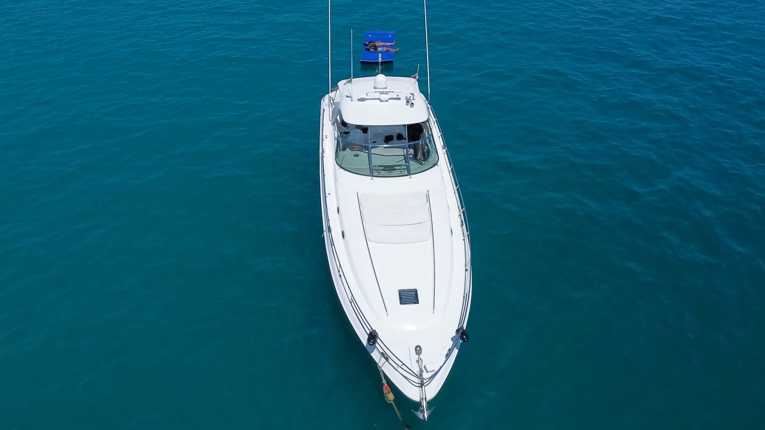Aerial view straight down on the Happy Ending's bow and sun pads, with a blue floating mat ahead