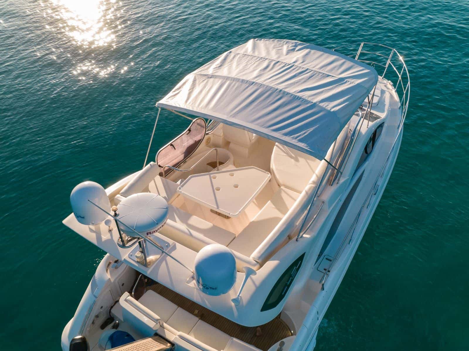 Flybridge from above with bimini cover, dining table, seating and sun cushions
