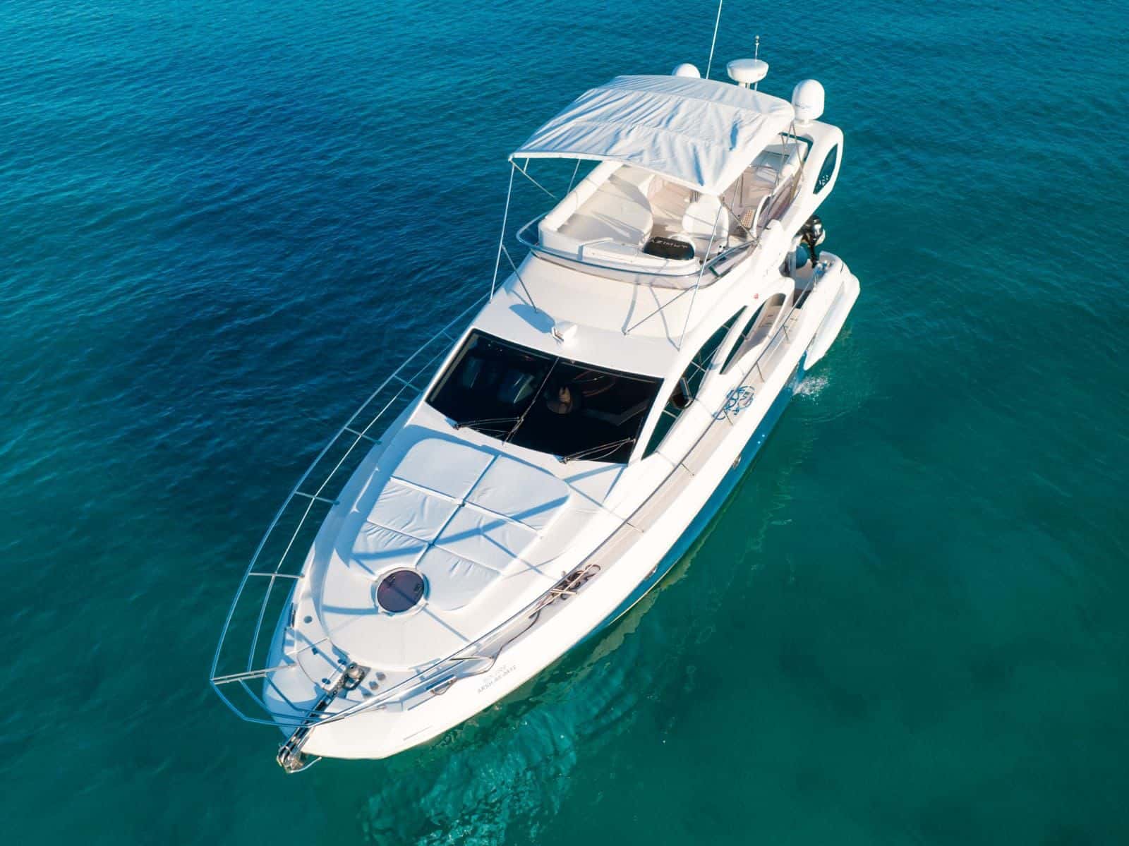 Golden seen from above on turquoise water, with bow sun pads, flybridge and bimini