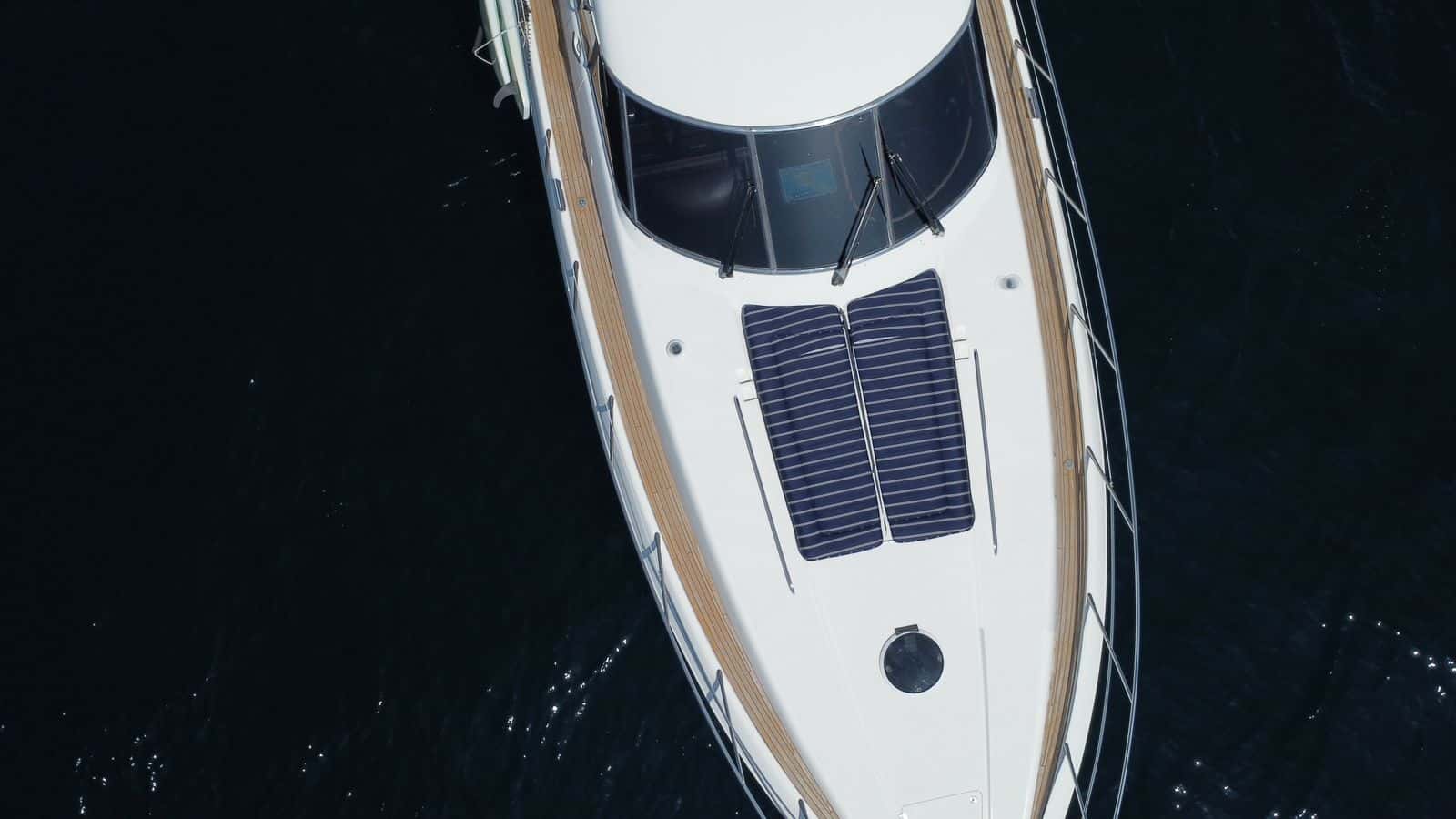 Aerial view of the bow with two navy striped sunpads on the foredeck above dark water