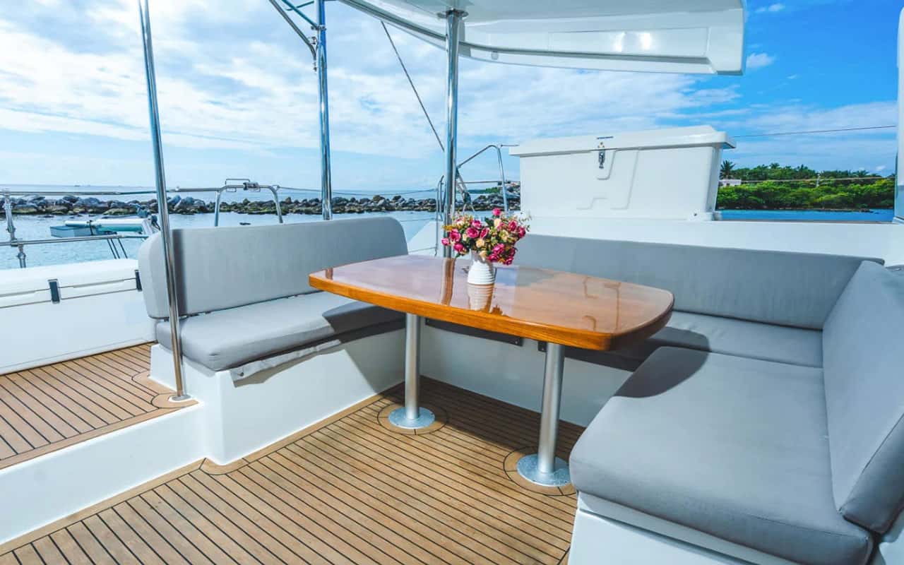 Cockpit dining table with grey cushioned benches and a flower vase