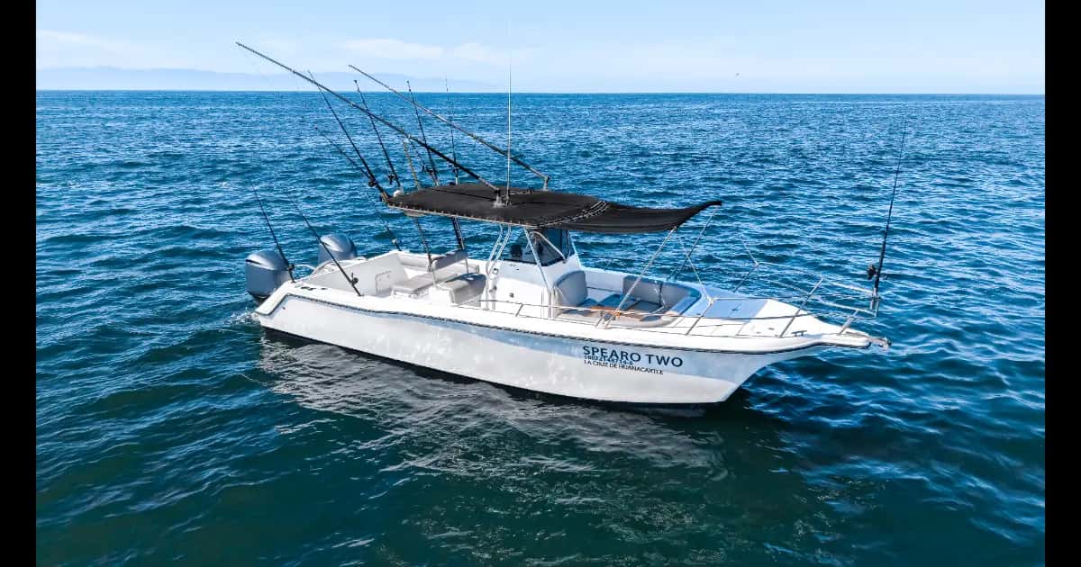 White center-console fishing boat with black T-top, rods and twin outboards, Spearo Two on the hull